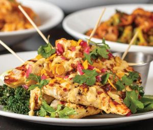 Healthy-looking grilled chicken topped with fresh salsa with broccoli and dipping sauce on the side.