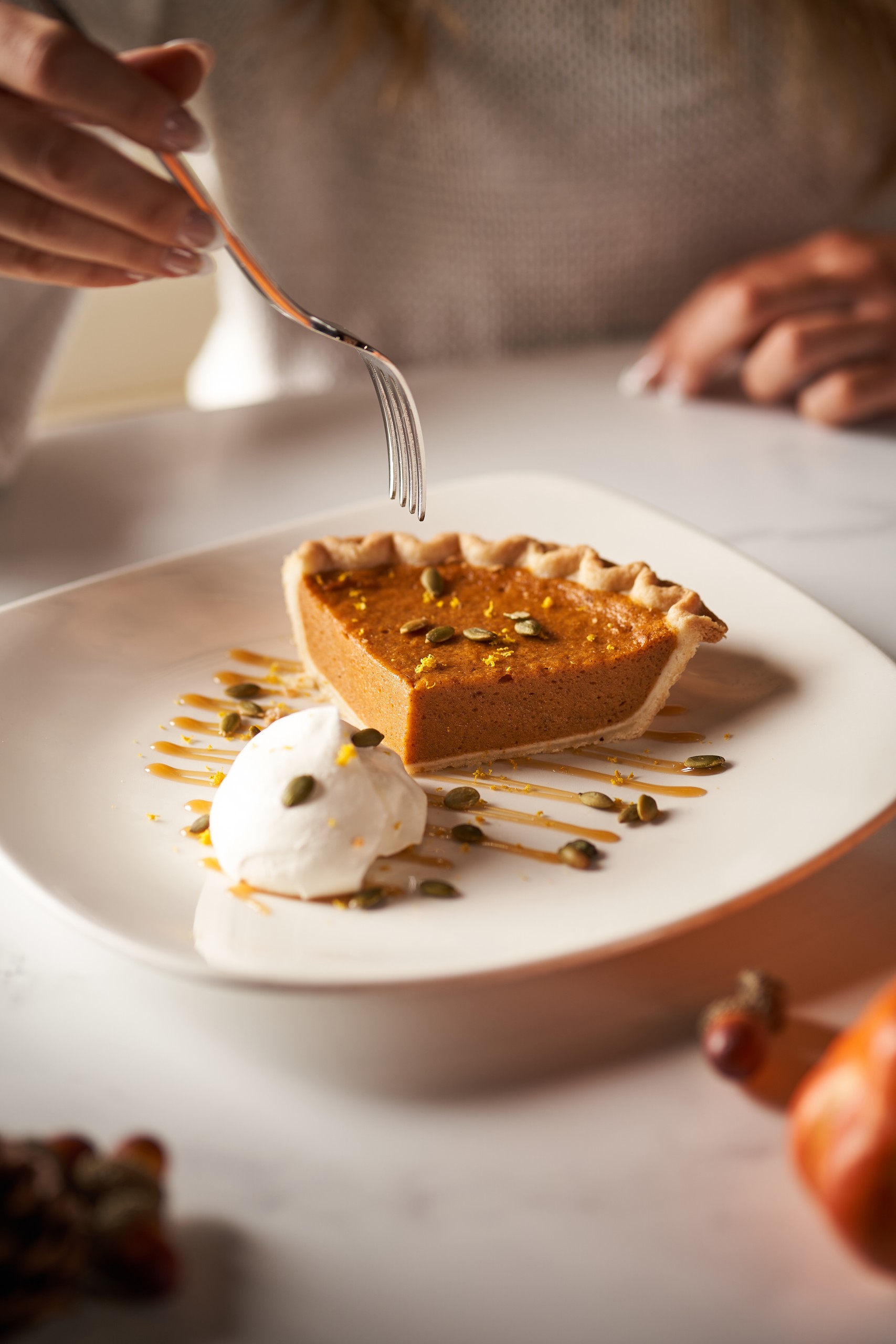 Person enjoying a slice of Pumpkin Pie